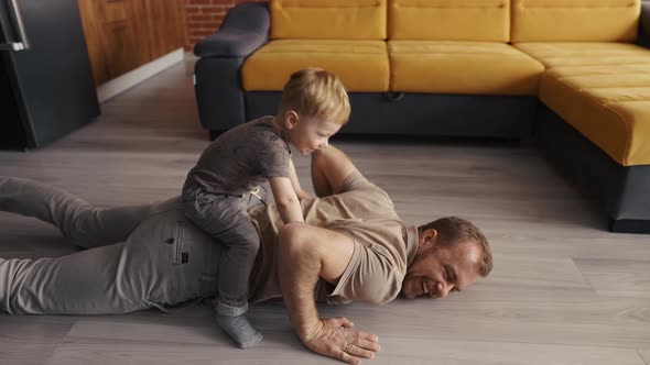 Father Happy Playing with His Son on the Back at Living Room