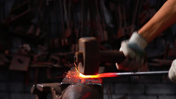 Slow Motion Close Up Hand with the Hammer of Blacksmith Man Forges a Metal Product in Dark Indoors