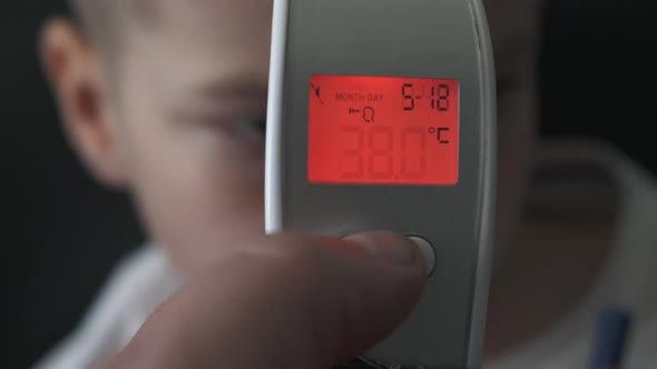 Dad Taking Sons Temperature Using a Digital Thermometer Covid 19 Virus Symptom, display 38 Degrees