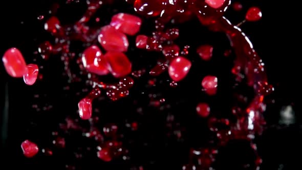 Pomegranate Grains Are Flying with Splashes of Sweet Juice on Black Background