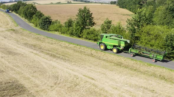 Aerial Drone Shot  a Combine Harvester Drives Down a Road in a Rural Area