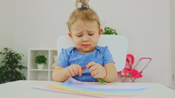 A Child Draws a Rainbow on Paper