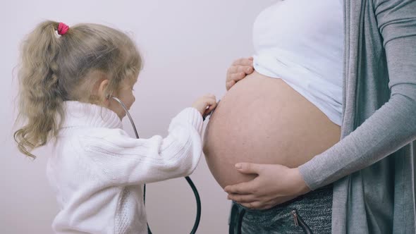 Girl Listens To Baby Heartbeat in Pregnant Mother Tummy