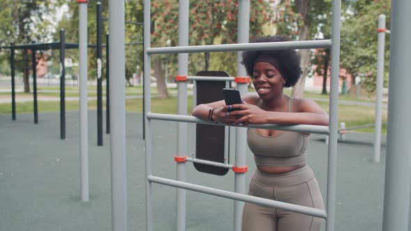 African American Woman Scrolling on Smartphone during Outdoor Training