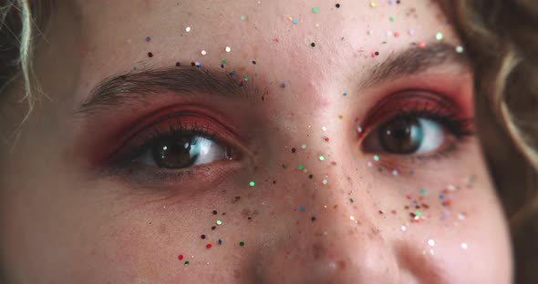 Profile of a woman face covered of glitter smiling and looking at the camera