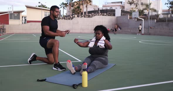 Curvy woman doing sport workout with her personal trainer outdoor