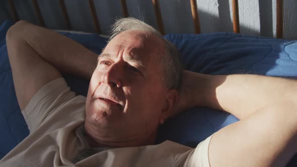 Senior man lying on bed at home