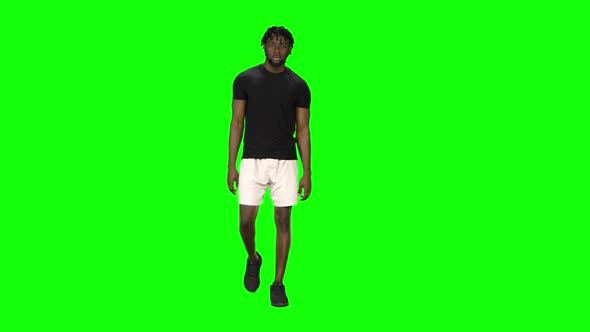 African American Man Is Walking at Green Screen, Chroma Key. Front View.