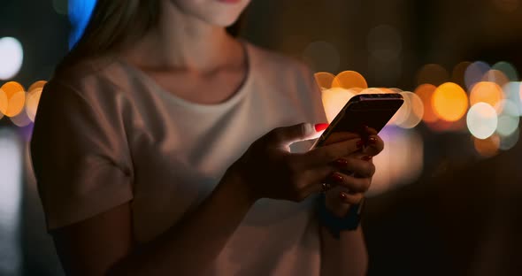 Close-up of a Mobile Phone in the Hands of a Girl in the City at Night