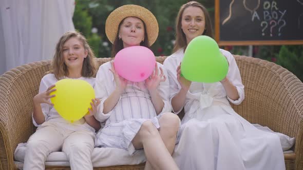 Front View Portrait of Joyful Pregnant Woman and Cute Girls Looking at Camera Throwing Colorful