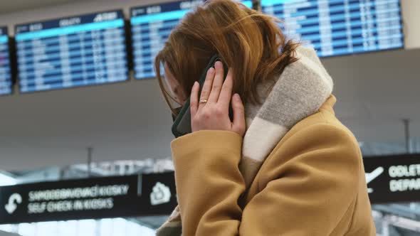 Young Brownhaired Woman in Black Facial Mask is Talking on Mobile Phone Against Background of