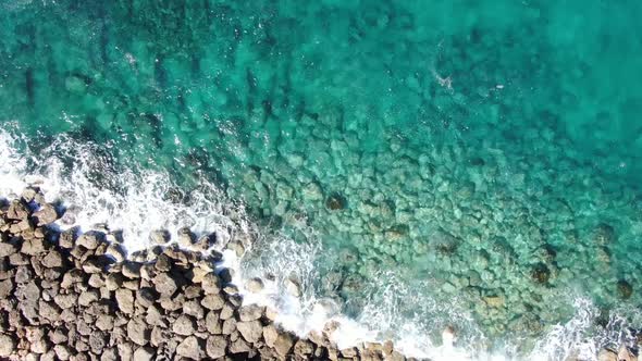 Turquoise Transparent Water Splashing Over Rocks in Ocean. Aerial Top View of Foamy Crystal Clear