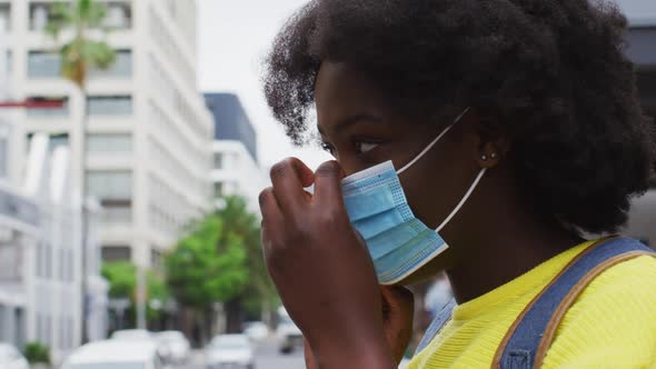 African american putting her mask on in street