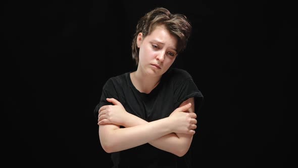 Slim Beautiful Depressed Woman with Crossed Hands Posing at Black Background