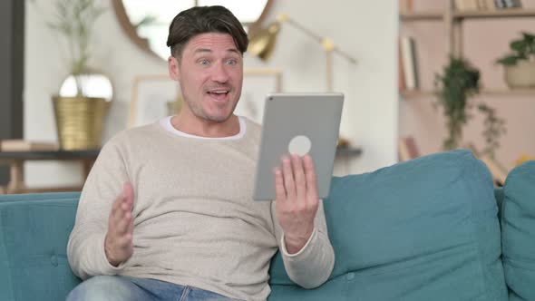 Middle Aged Man Celebrating on Tablet, at Home