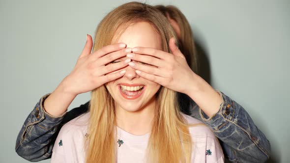 Girl surprising her female best friend. She is covering her eyes and hugging  from behind