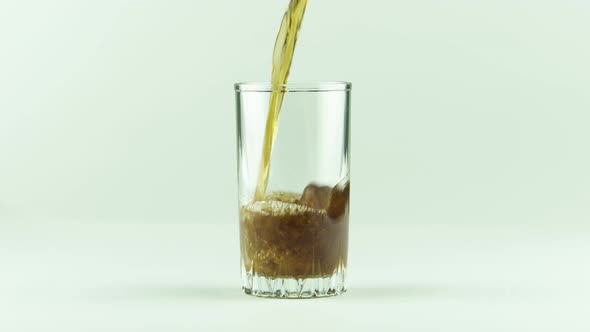 Cola Is Poured Into Glass Full of Bubbles and Foam Isolated on White Background