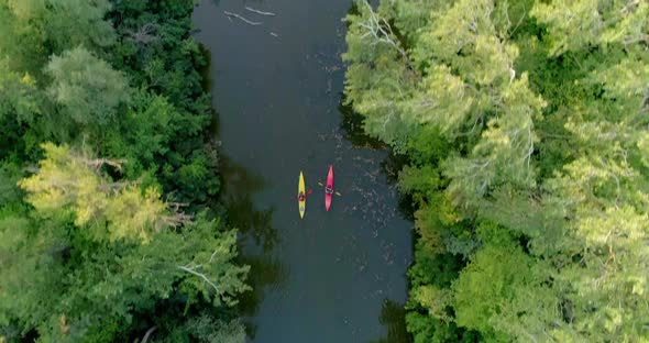 Two kayaks are sailing along a scenic river. Aerial view.