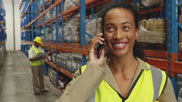 Young female worker using smartphone in a warehouse