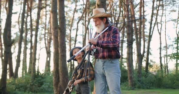 Senior Man in Hat and His Small Handsome Grandson which Talking while Going Fishing 