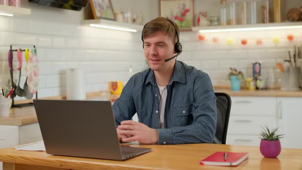 Smiling businessman wear wireless headset making conference video call on laptop. 