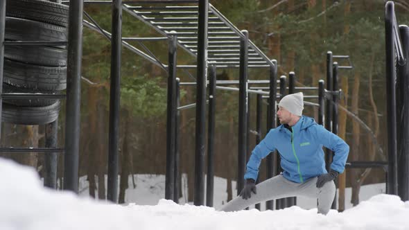 Active Man Stretching Legs at Outdoor Gym in Winter