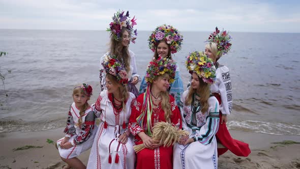 Group of Ukrainian Young Women and Girl Sitting on Sandy River Beach Smiling Looking Around