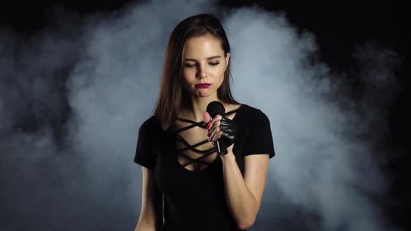 Singer Sexually Dances and Sings Songs in a Microphone at a Concert. Black Smoke Background. Slow