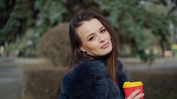 Face of a luxury young woman. Portrait of attractive model with long dark hair in warm coat holding 