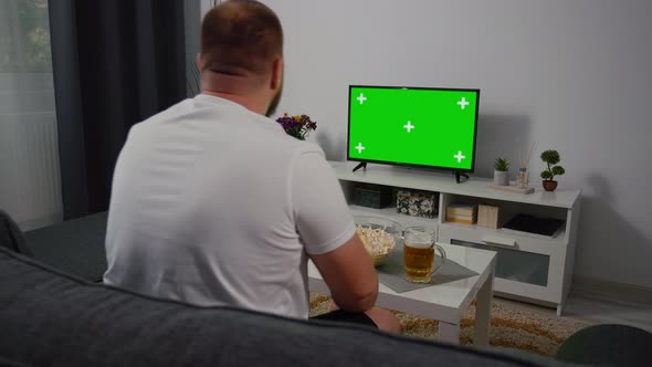 At Home male Soccer Fan Sitting on a Couch Watching Green Screen