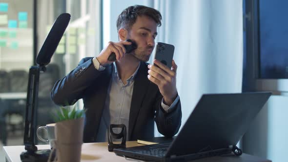 Young Businessman Sits at His Desk in the Office and Shaves at the Workplace Works Overtime Lack of