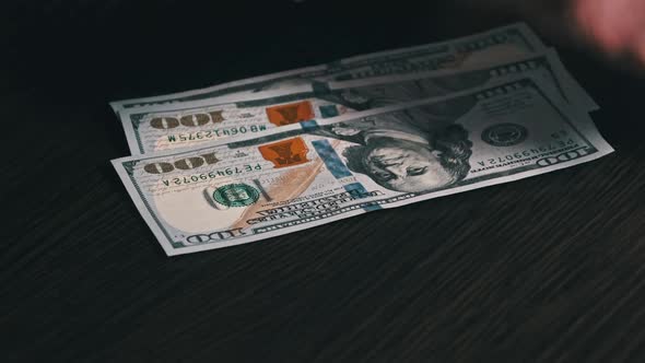 Counting Old Hundred Dollar Banknotes on a Black Wooden Table