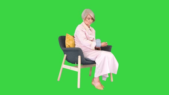 Aged Woman Measuring Blood Pressure Reaction on a High or Low Pressure on a Green Screen Chroma Key