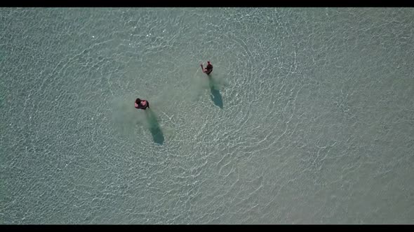 Two people posing on paradise tourist beach lifestyle by transparent water with white sandy backgrou