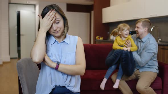 Tired Depressed Young Caucasian Mother Woman Feel Very Annoyed of Active Father and Daughter Child