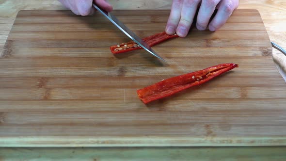Knife Deseeding Half A Long Red Chilli on Wooden Chopping Board