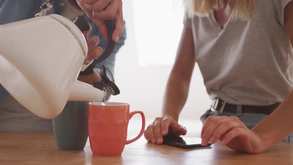 Mid section man pouring water in coffee cup on the table