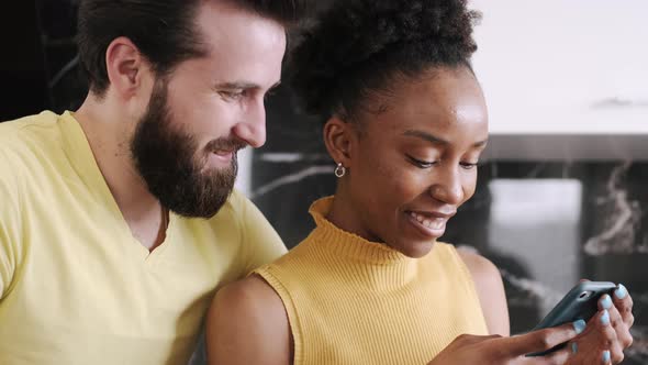 Multi Racial Couple Checking Something in Smartphone Standing in the Kitchen