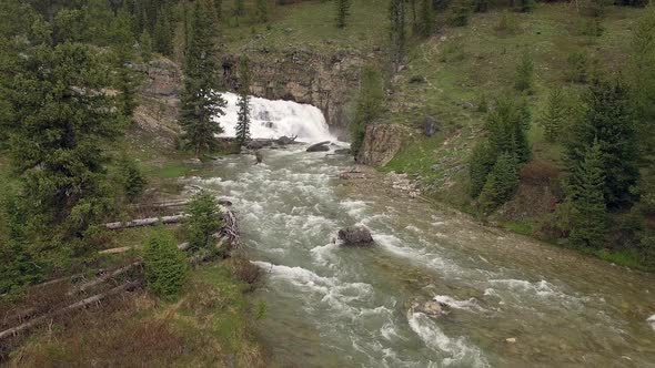 Flying over river towards waterfall in the Wyoming mountains