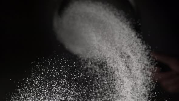 Dusting flour on black background. Slow Motion.