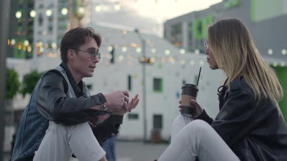 Young People Communicate Boy and Girl Talks Near a Modern Residential Area Evening in the City