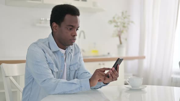 African Man Using Smartphone at Home 