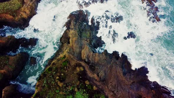 Waves crash into a rocky cove eroded out of tall cliffs in California