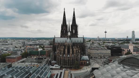 Aerial drone footage circling the Cologne Cathedral along the shore of the Rhine River in Germany.
