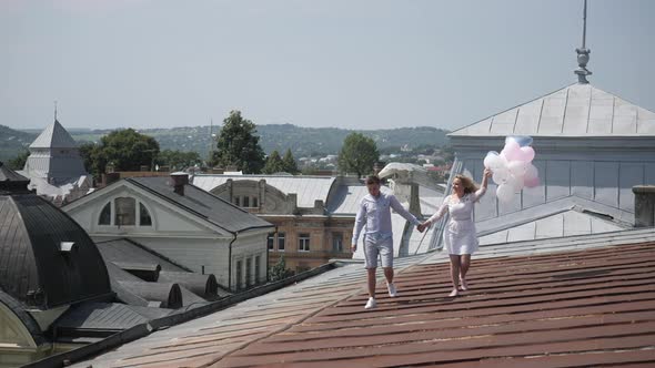 Couple with balloons walking on a roof 