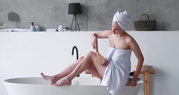 Half Naked Pretty Woman Wrapped in Bath Towel Using a Brush Massager Doing Smoothing Anticellulite