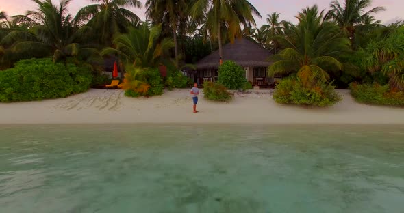 Aerial view of a man taking a selfie on a beach at a tropical island resort hotel