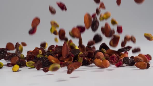 Healthy trail mix falling onto a white surface in slow motion