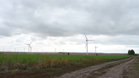 Large wind turbines with blades in the wind park on the background cloudy sky.