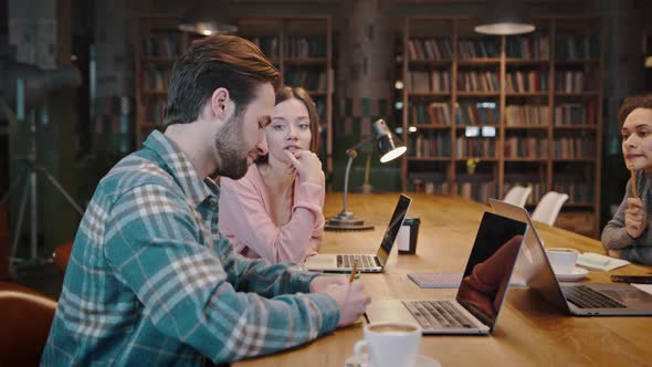 Confident Young Woman Works in Library Together with Multiethnic Coworkers